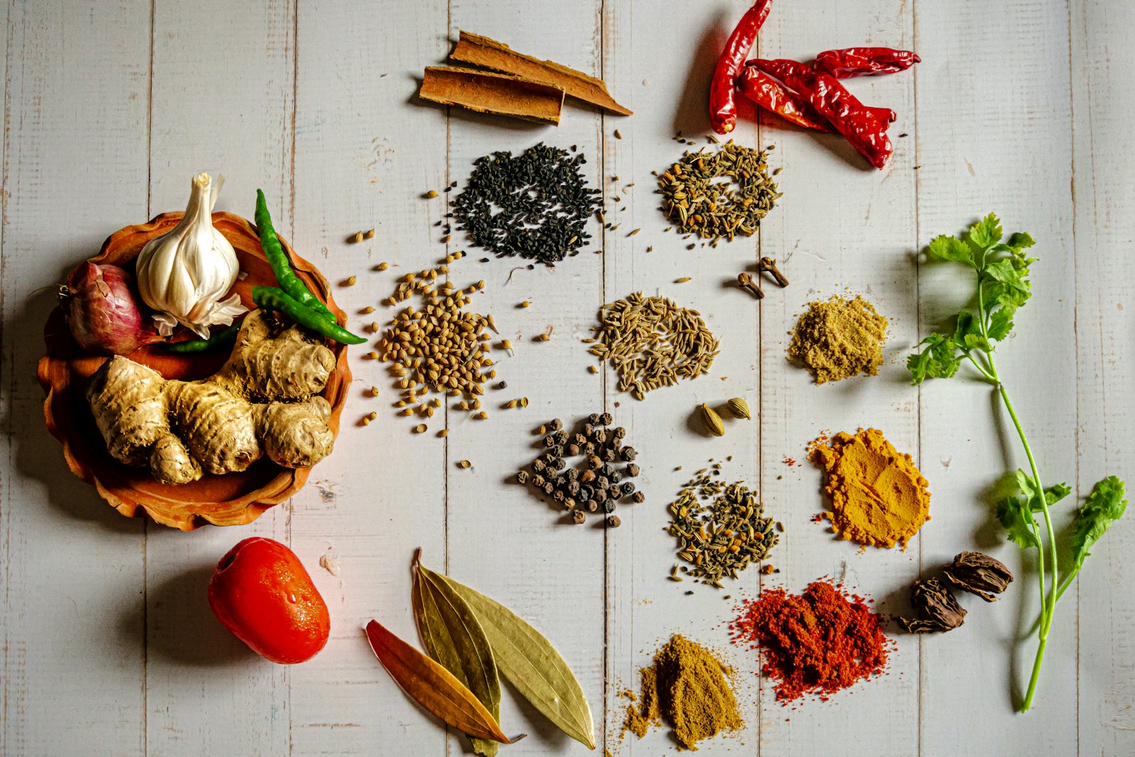 Haldi, lal mirch, jeera, dhaniya aur sabut masale safed lakdi par saje hue