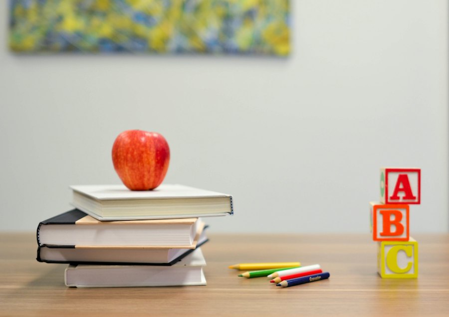 A stack of books with a red apple and ABC blocks on a desk