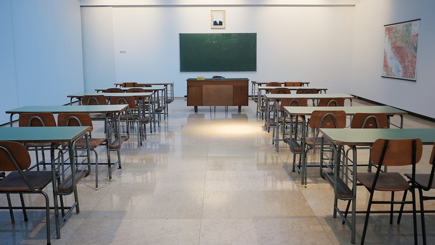 A bright, clean classroom with rows of desks and a green board